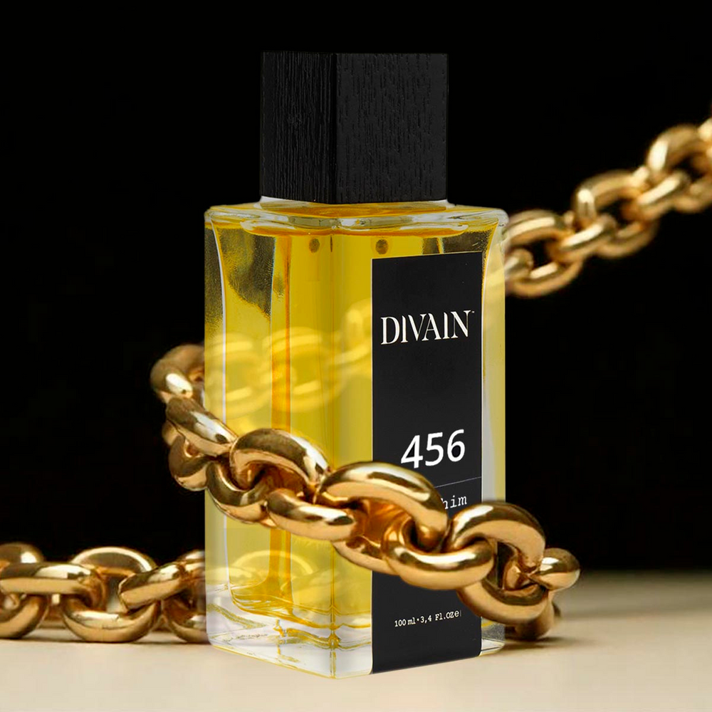 Perfume divain-456 rodeado por una cadena de oro sobre un fondo negro